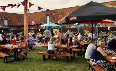 Festivalweide met picknicktafels en parasols